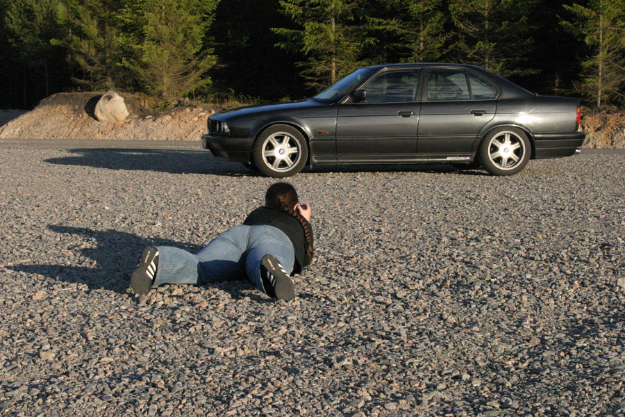 Fotograf som ligger på marken och fotograferar BMW från låg vinkel