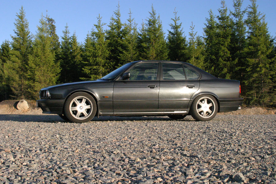 BMW fotograferad från låg vinkel med sky och skog i bakgrunden