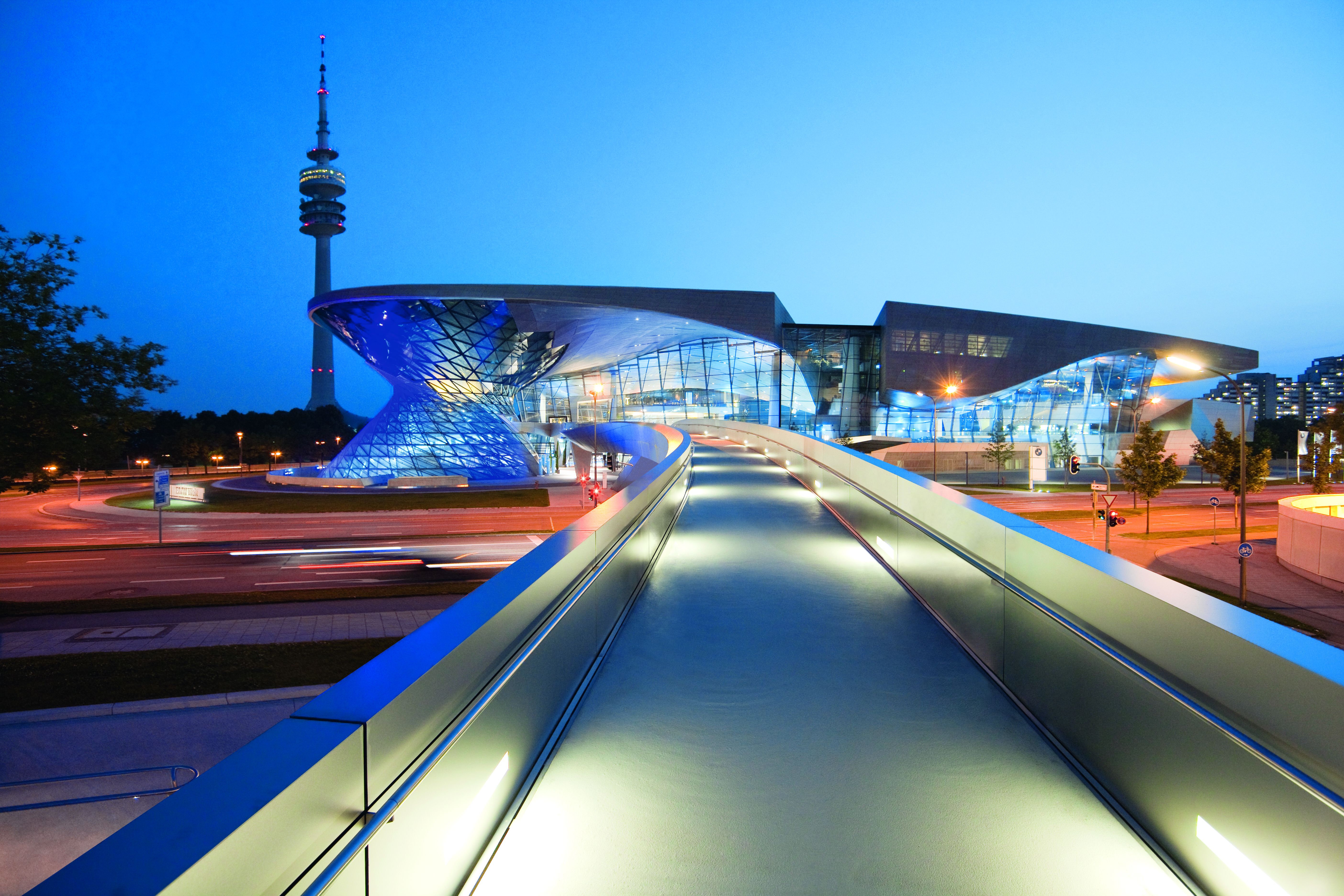 BMW Welt i München i kvällsbelysning med Olympiatornet i bakgrunden