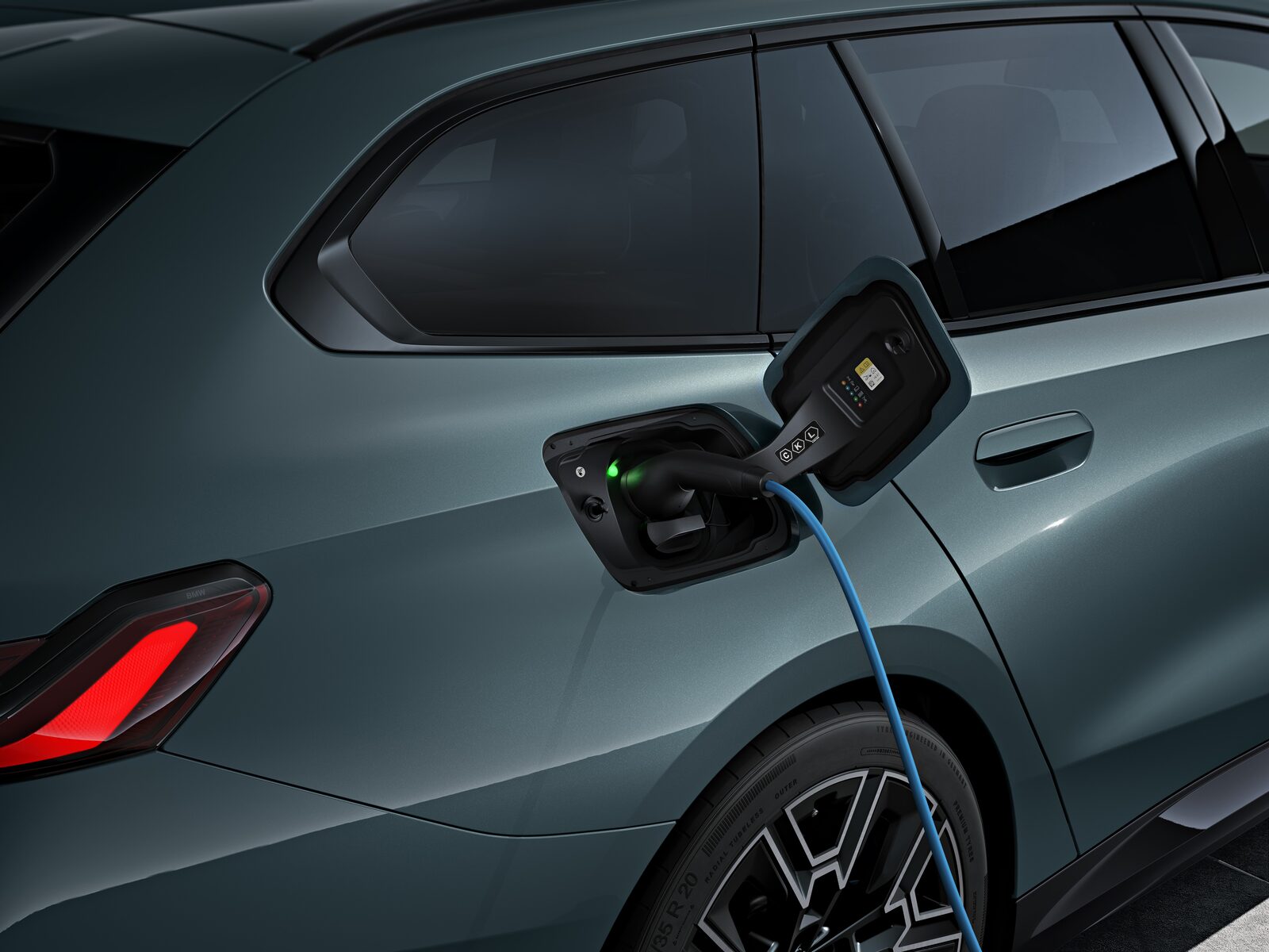 BMW i5 Touring laddar vid en publik snabbladdare