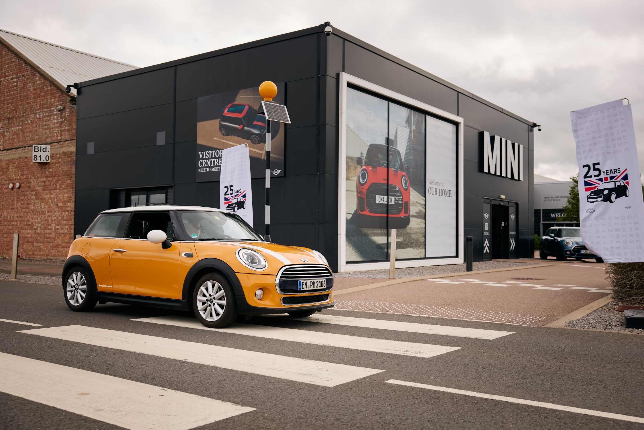 Orange MINI Cooper D med vita motorhuvsränder utanför Plant Oxford
