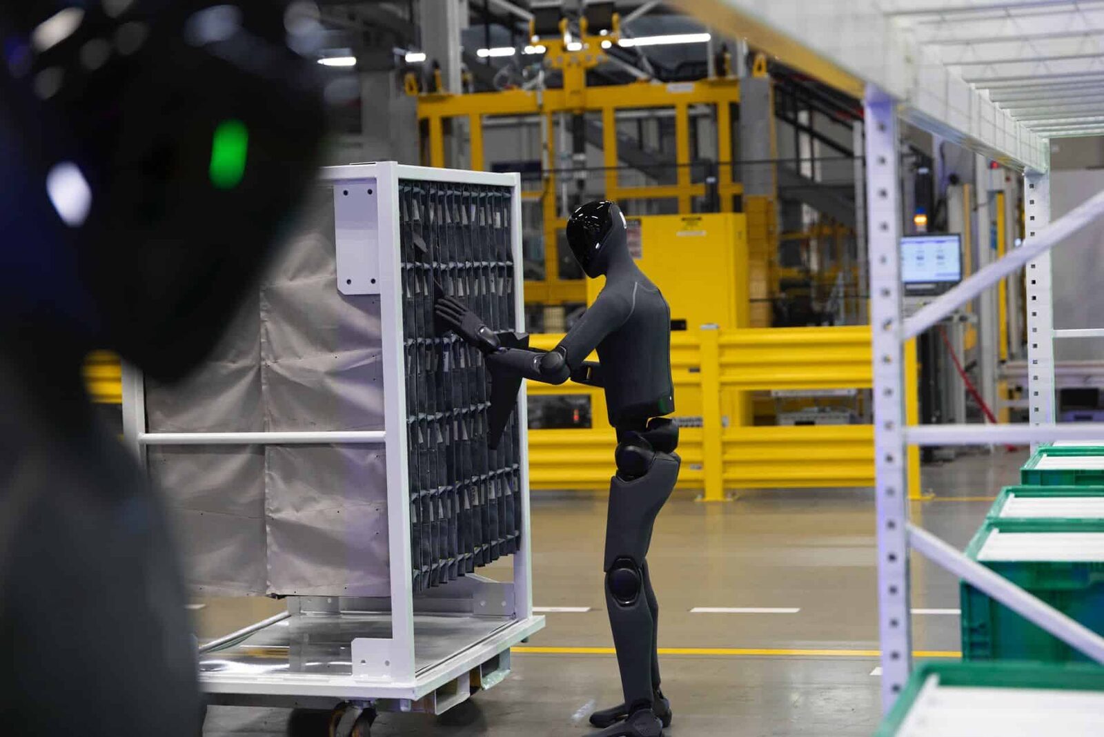 Figure 03-robot lastar delar i en vit sekvensvagn i fabrikshallen