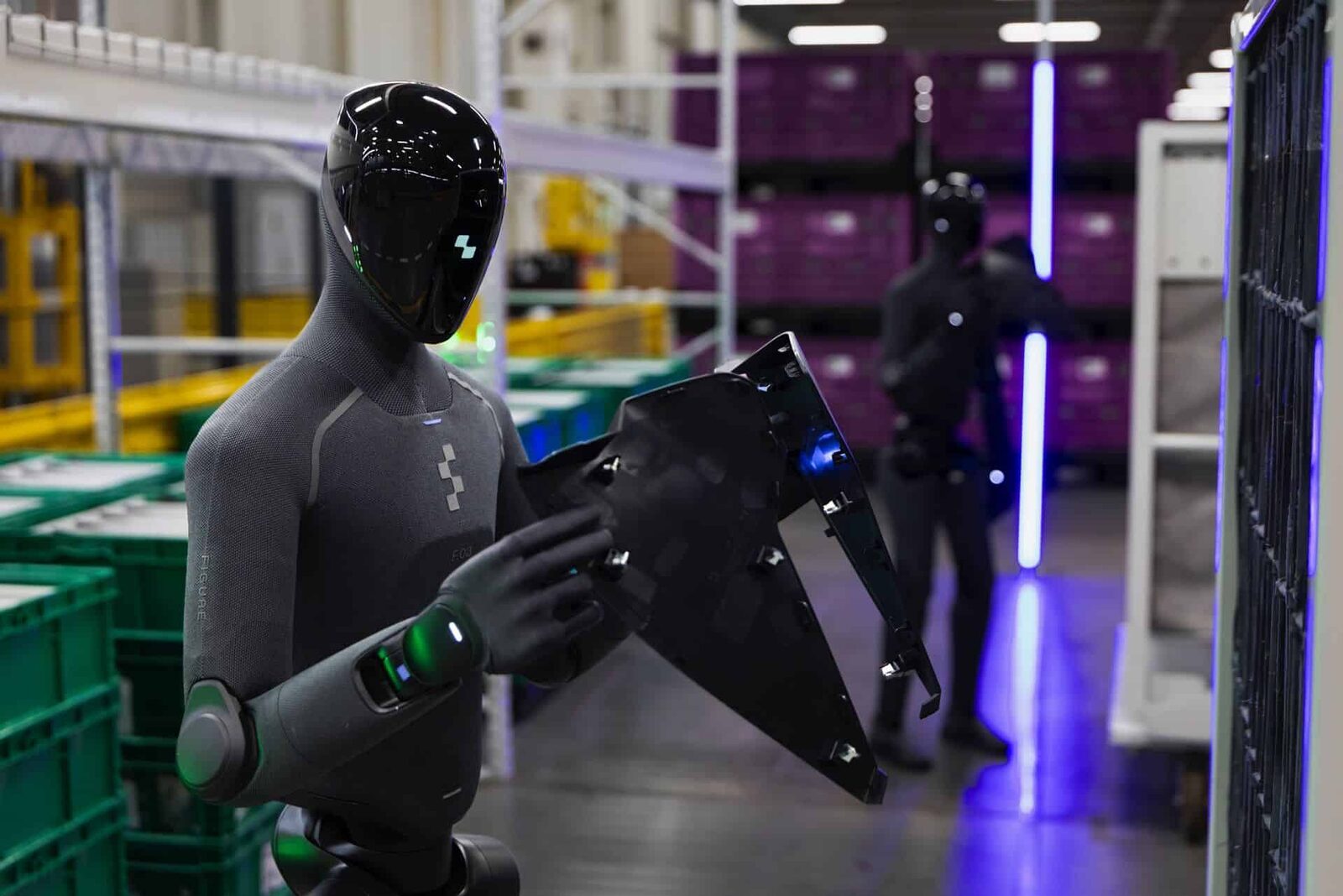 Närbild på Figure 03 som håller en svart plastdetalj, märkningen F.03 syns på bröstet