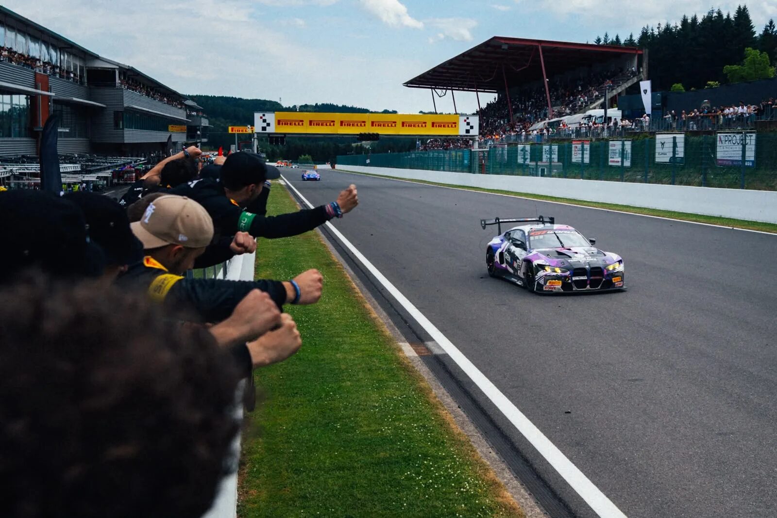 ROWE Racings lila BMW M4 GT3 EVO rullar i mål på Spa-raksträckan medan teamet jublar över muren