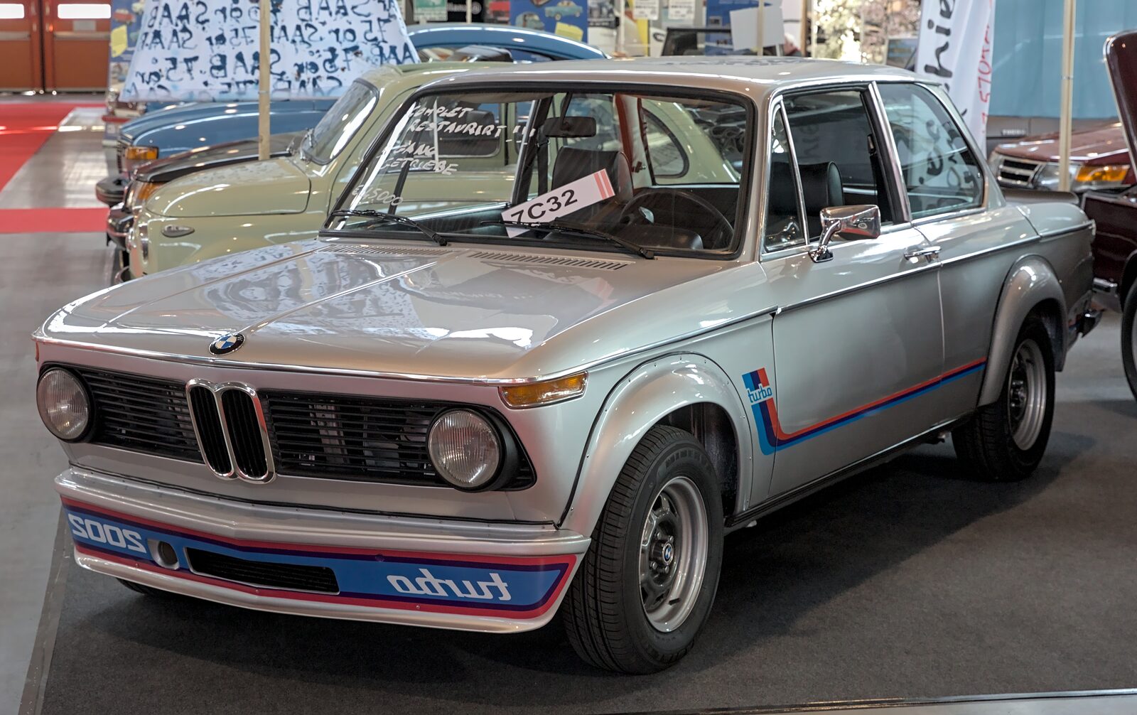 Silverfärgad BMW 2002 turbo snett framifrån med breddade skärmar och spegelvänd turbo-dekal på frontspoilern