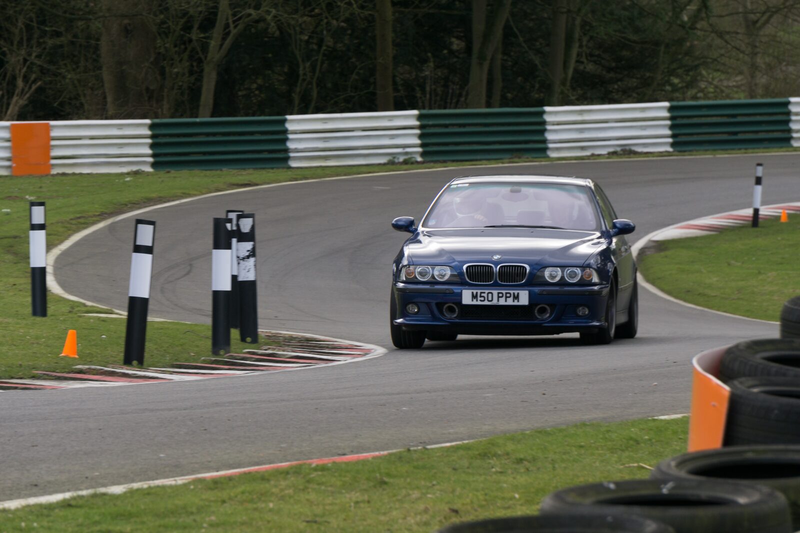 Blå BMW M5 E39 körs på en bana, sedd framifrån