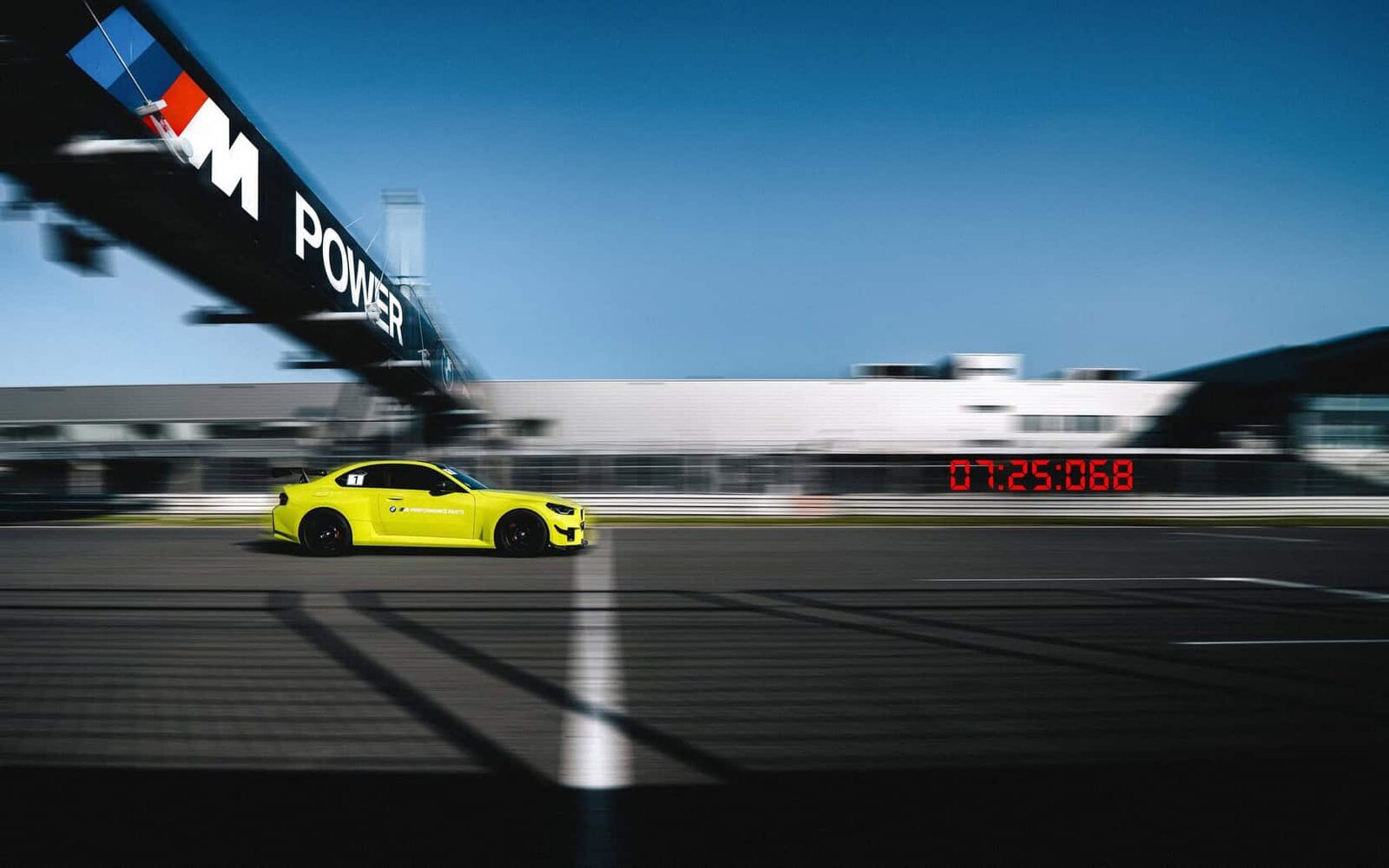 Neongul BMW M2 med M Performance Track Kit passerar mållinjen på Nürburgring med klockan på 07:25:068
