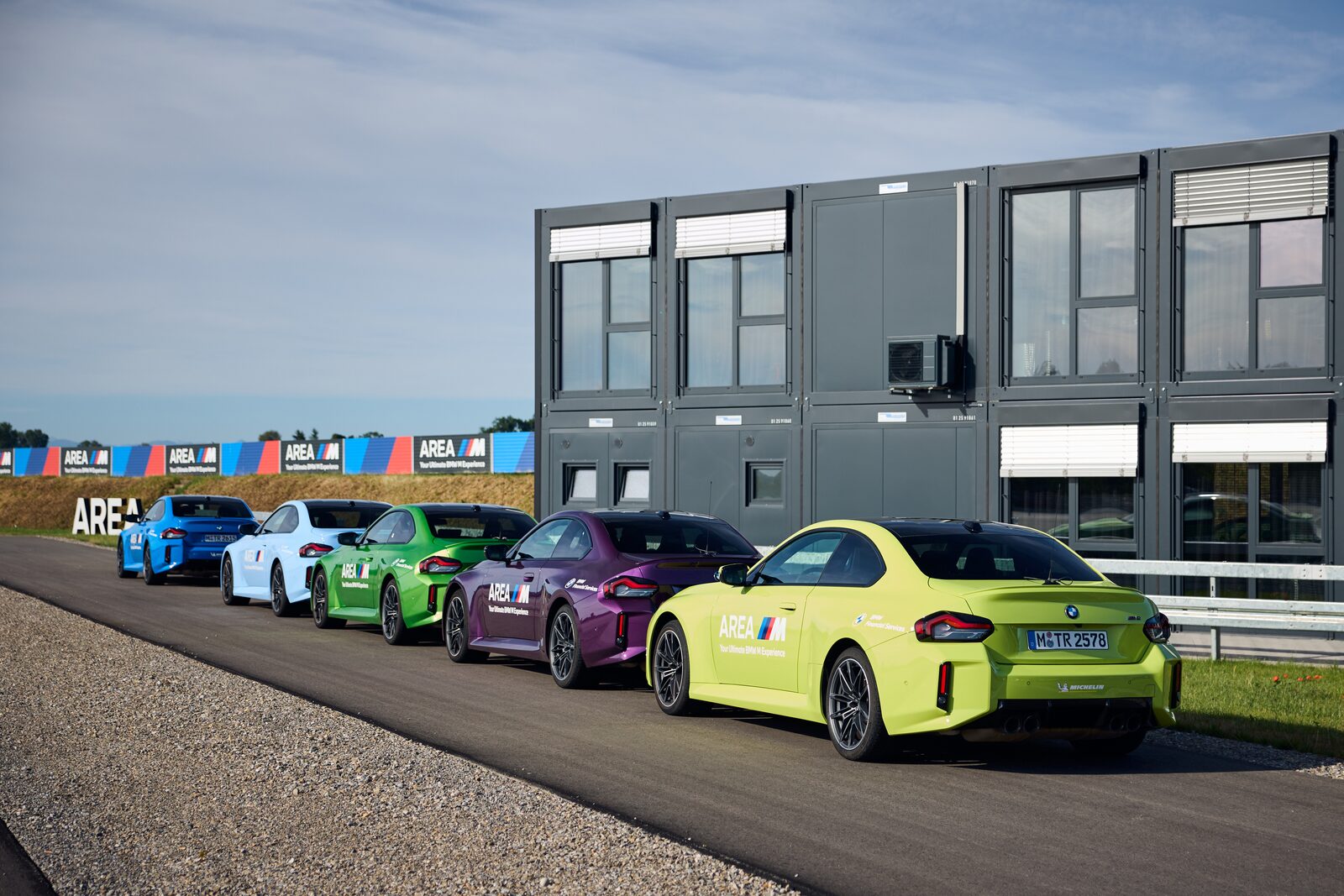 Rad av färgglada BMW M2 med AREA M-dekor uppställda framför anläggningen i Memmingen