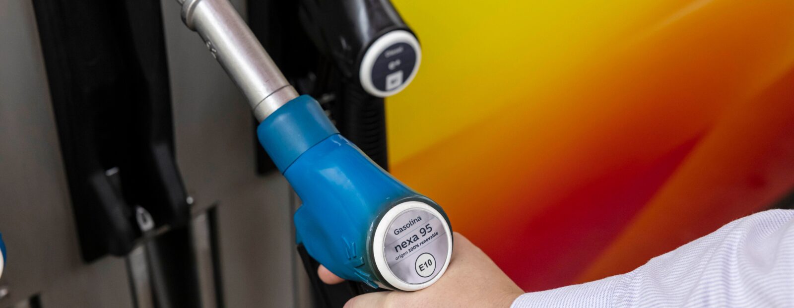 Hand som håller ett munstycke märkt Nexa 95, Repsols 100 procent förnybara bensin, vid en tankstation