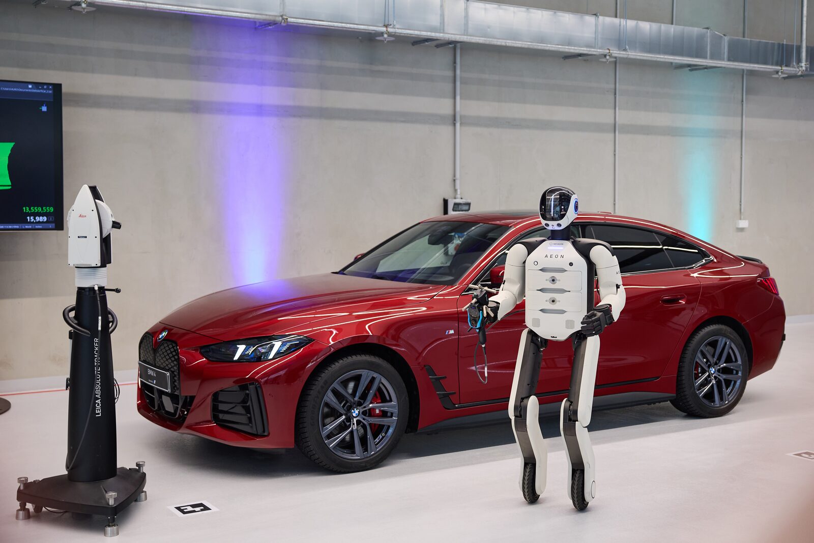 Humanoid robot bredvid en röd BMW 4-serie i BMW:s Physical AI-program