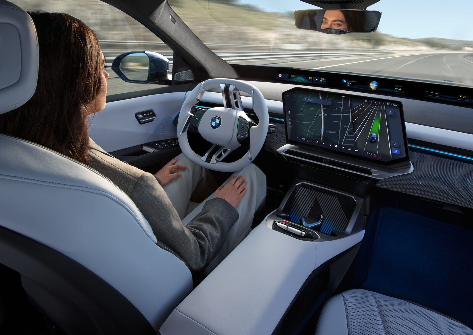 Förare i BMW iX3 med händerna i knät som tittar mot sidospegeln för att bekräfta ett filbyte
