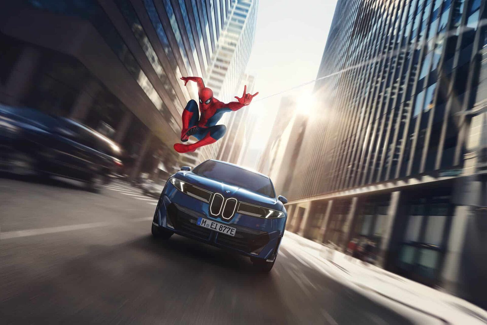 Blå BMW iX3 i fart mellan skyskraporna med Spider-Man svingande i sin tråd