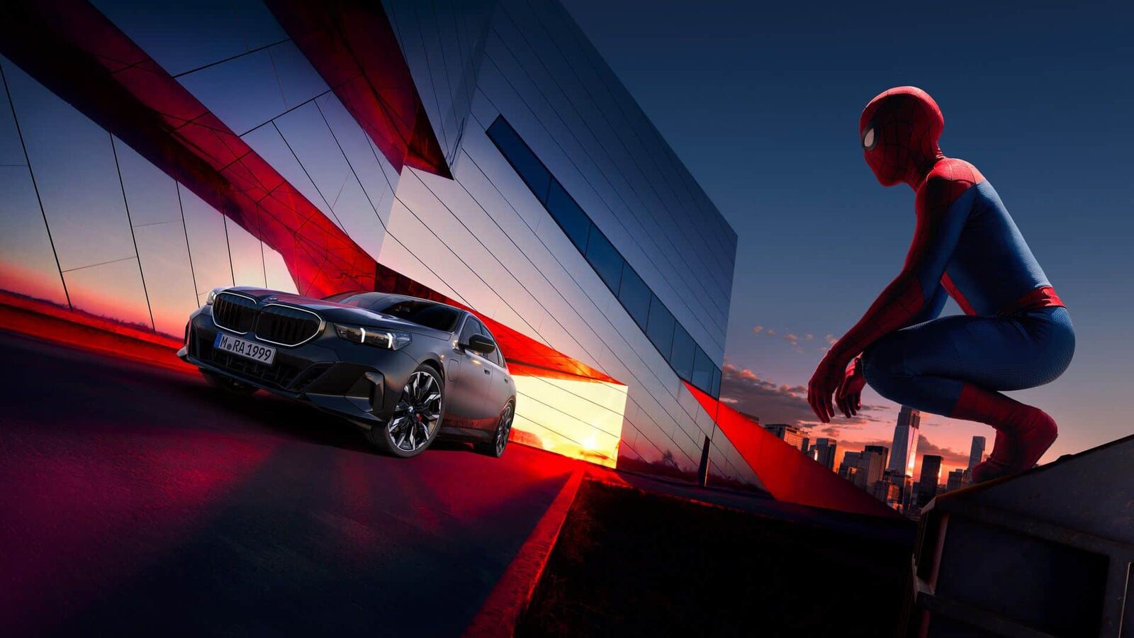 Svart BMW 5-serie i skymningen framför en speglande byggnad med Spider-Man på kanten