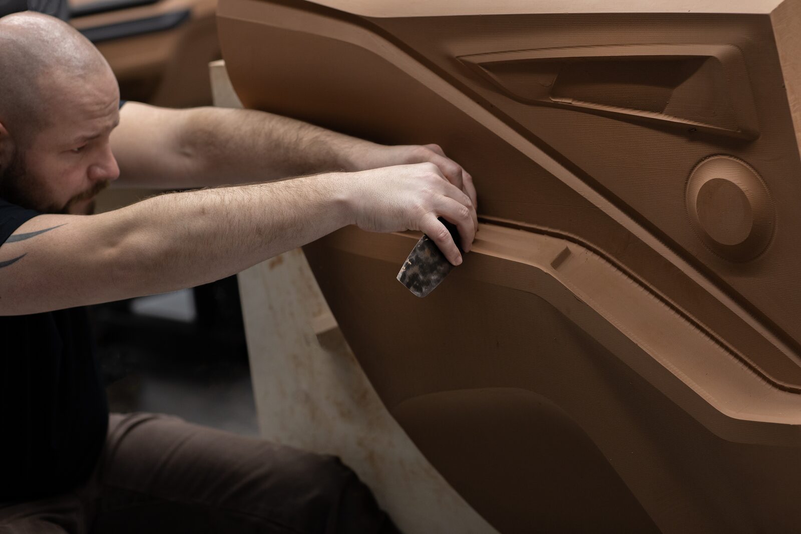 BMW-formgivare bearbetar en dörrsida i lermodell med handverktyg