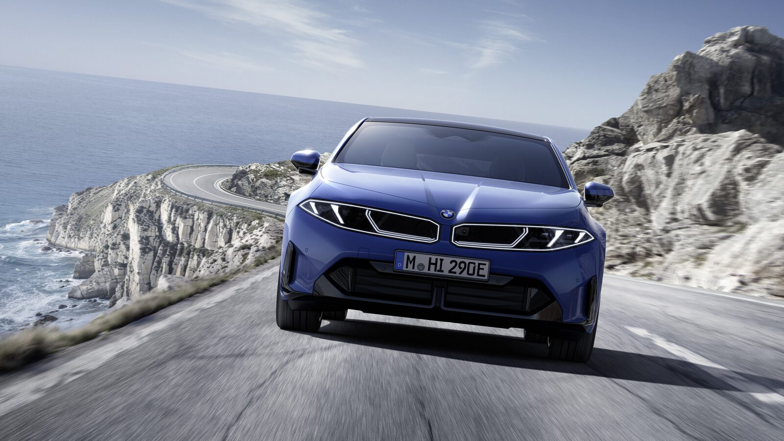 Blå BMW i3 sedan i fart på en kustväg