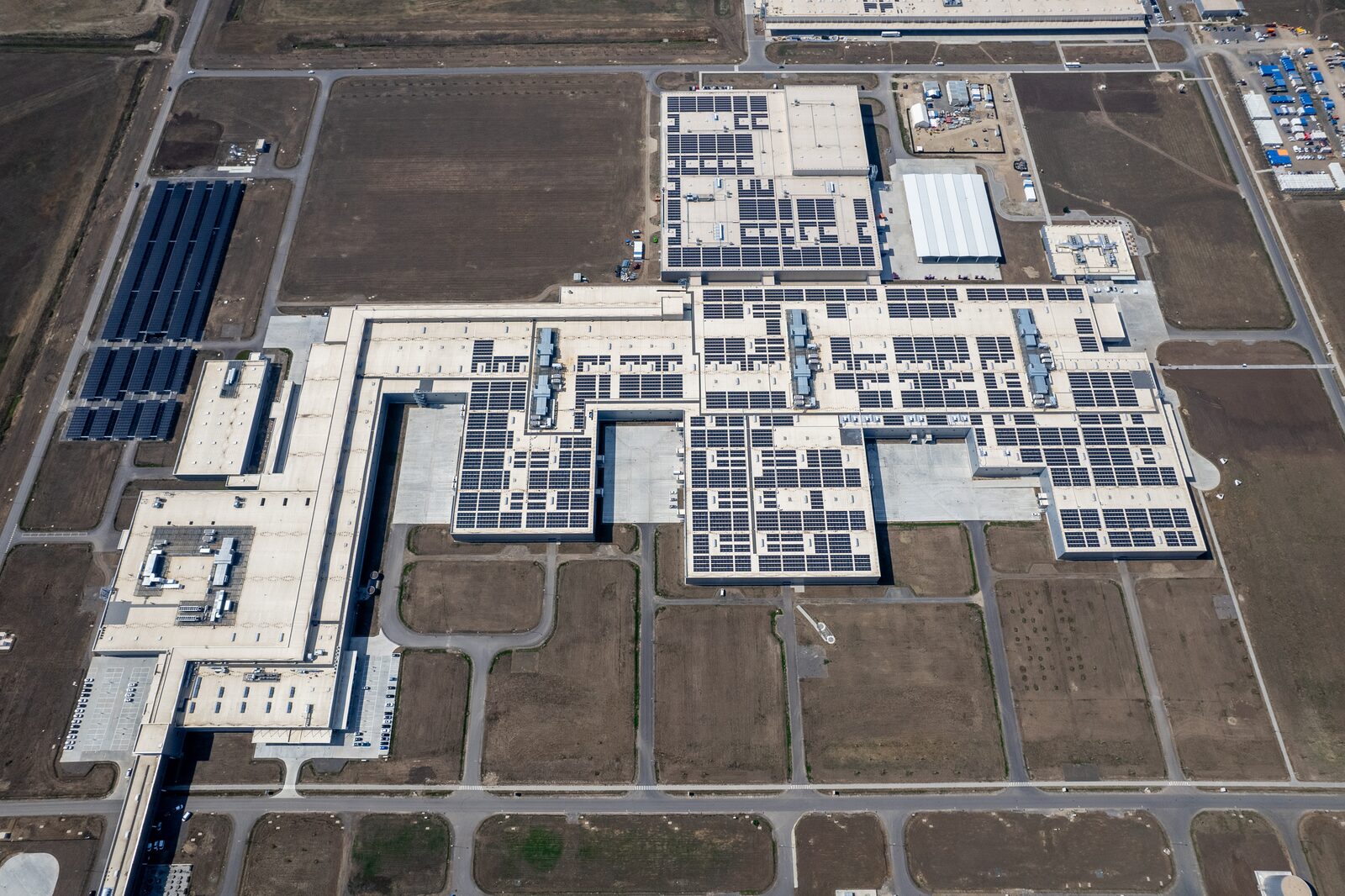 Flygbild över BMW Group Plant Debrecen med solpaneler på fabrikstaken och en solcellspark på fälten intill
