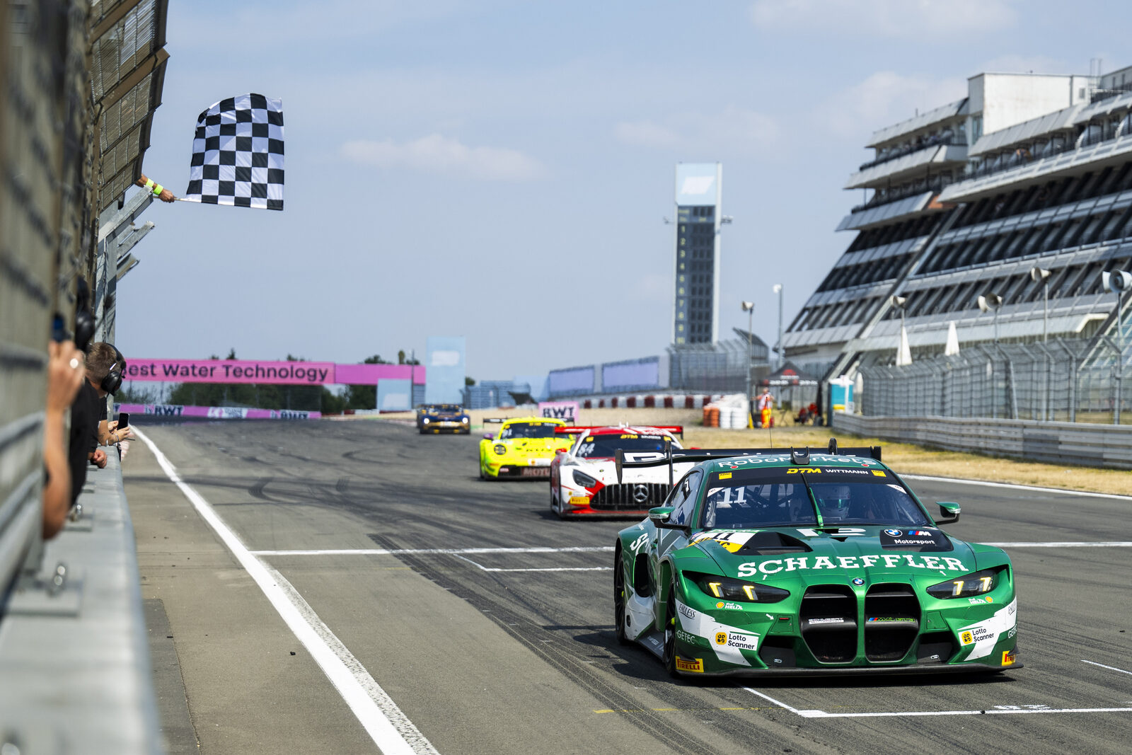 Marco Wittmanns gröna Schaeffler BMW M4 GT3 EVO passerar mållinjen under den rutiga flaggan på Nürburgring
