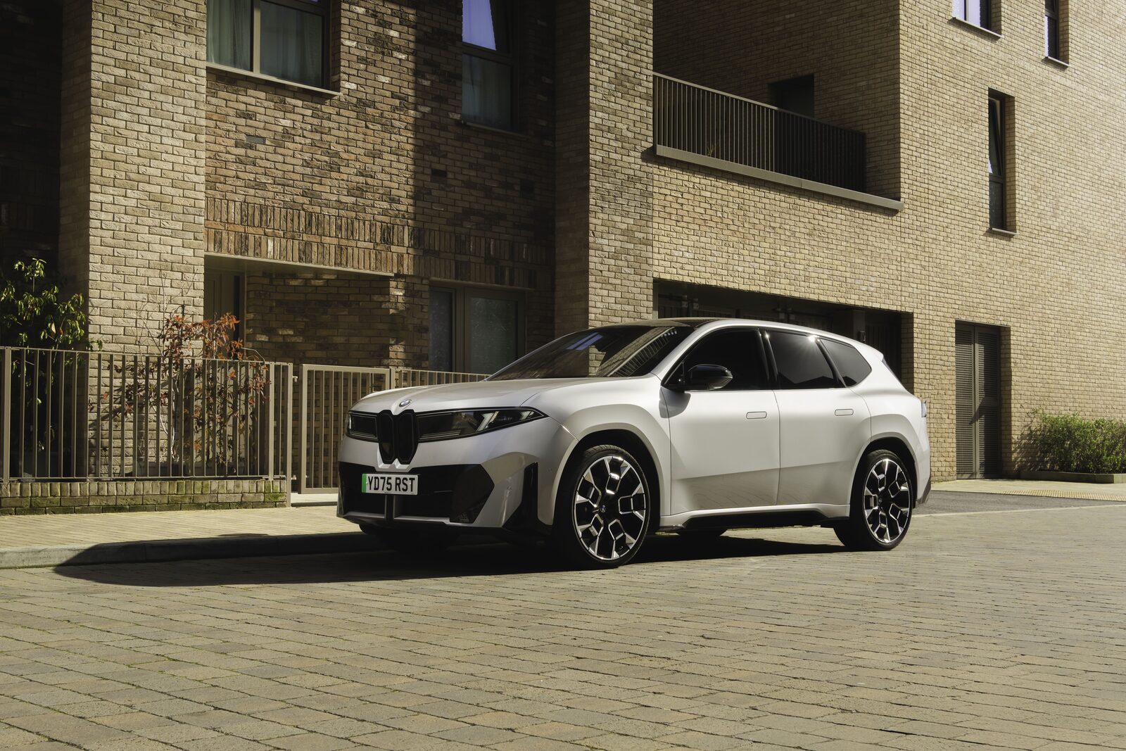 Vit BMW iX3 med brittiska registreringsskyltar parkerad framför ett tegelhus