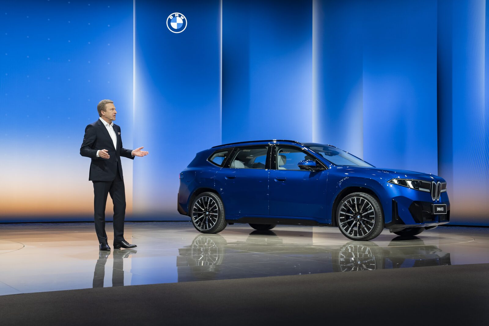 Blå BMW iX3 Long Wheelbase i profil på scen under bilmässa i Kina