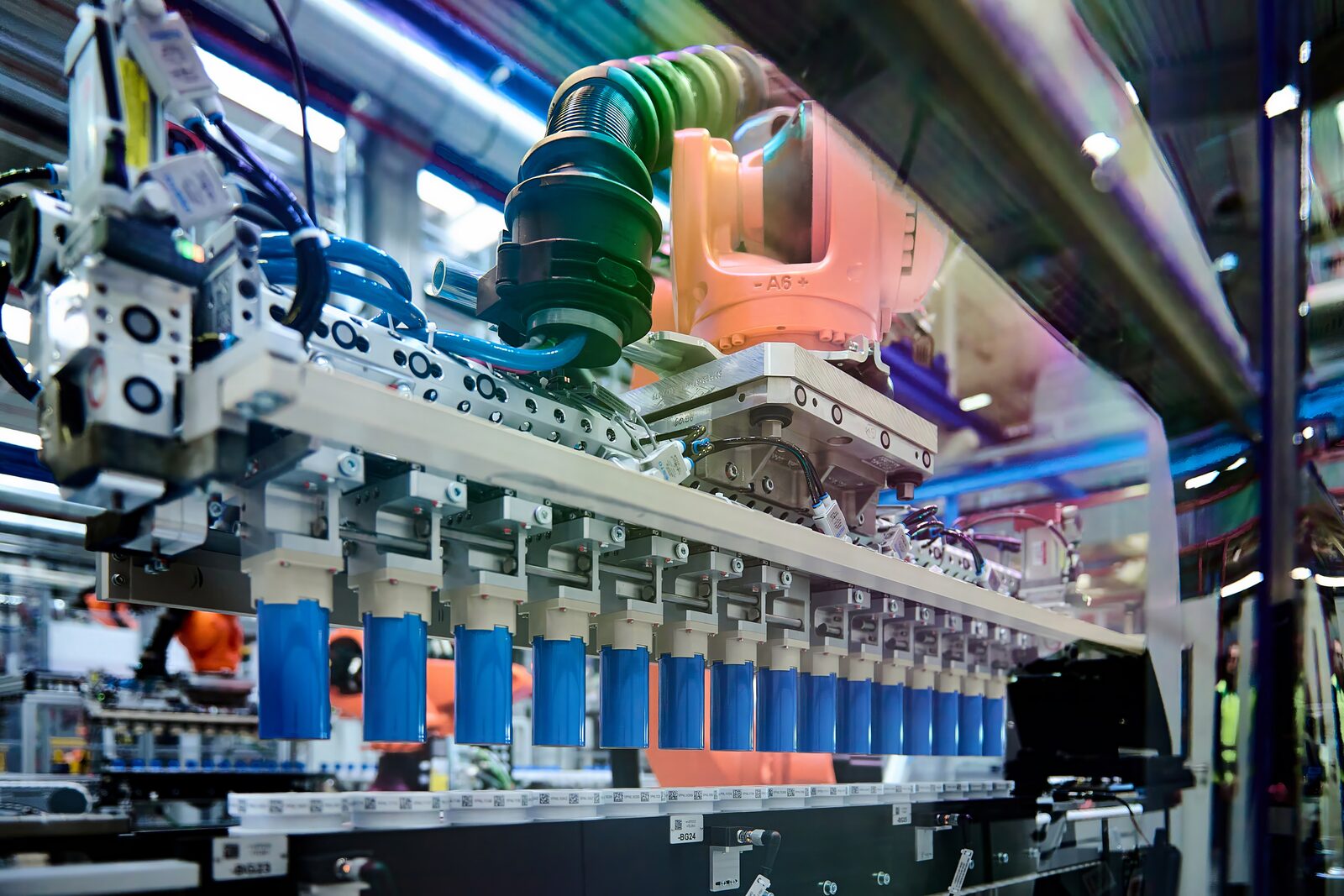 Rad av blå cylindriska battericeller på ett löpande band i BMW:s cellfabrik