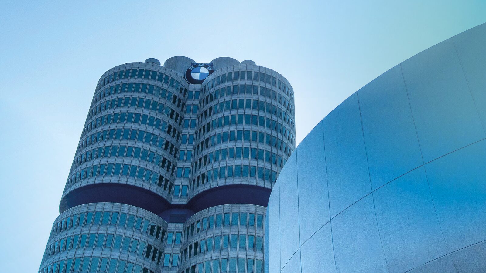 BMW:s huvudkontor sett underifrån mot blå himmel intill BMW Welts välvda fasad