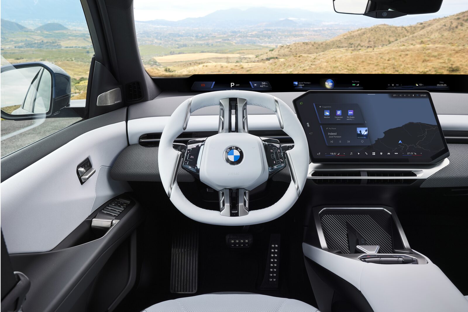 Förarplatsen i nya BMW iX3 med Panoramic Vision längs vindrutan och centraldisplayen till höger