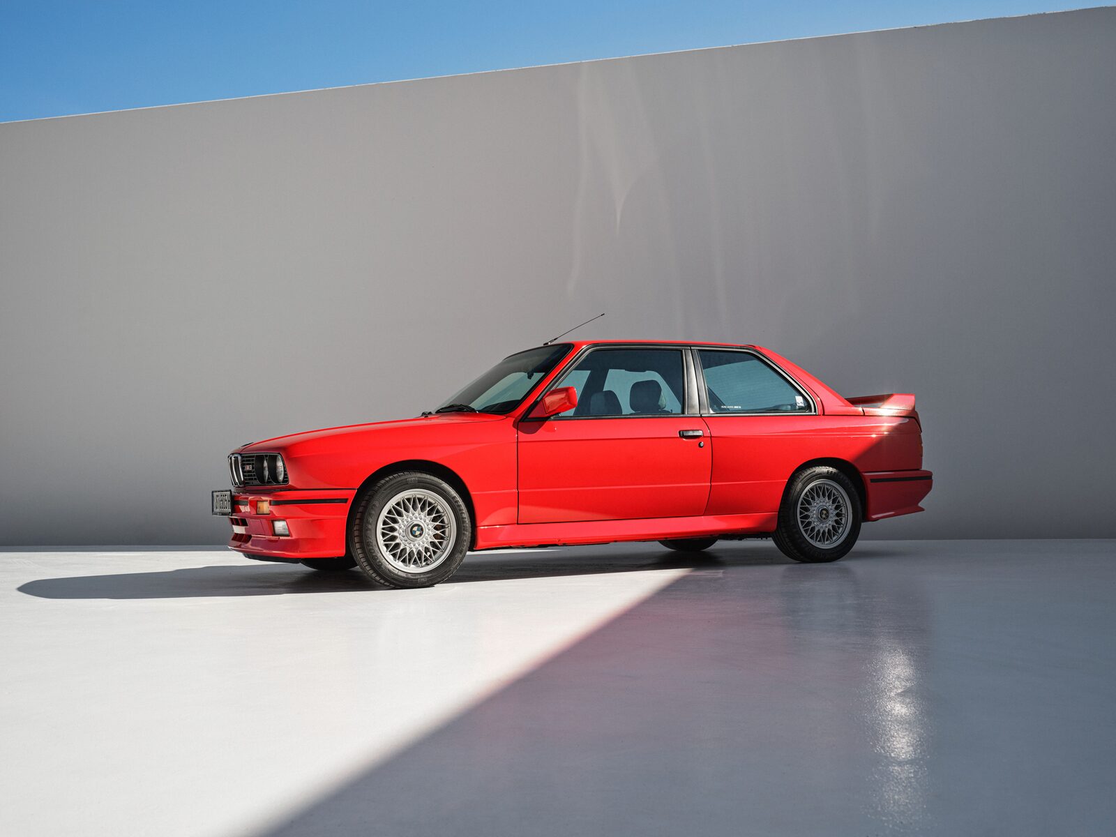 Röd BMW M3 E30 i profil i studiomiljö