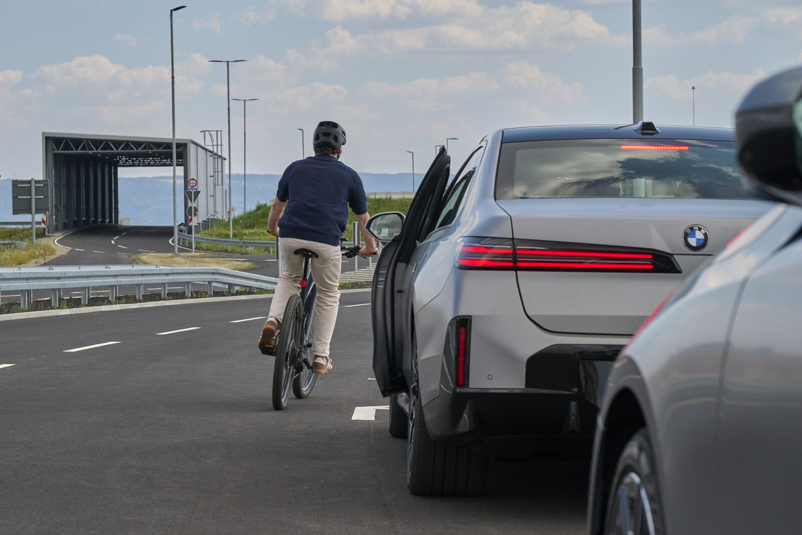 En cyklist passerar en parkerad BMW i det ögonblick föraren öppnar dörren
