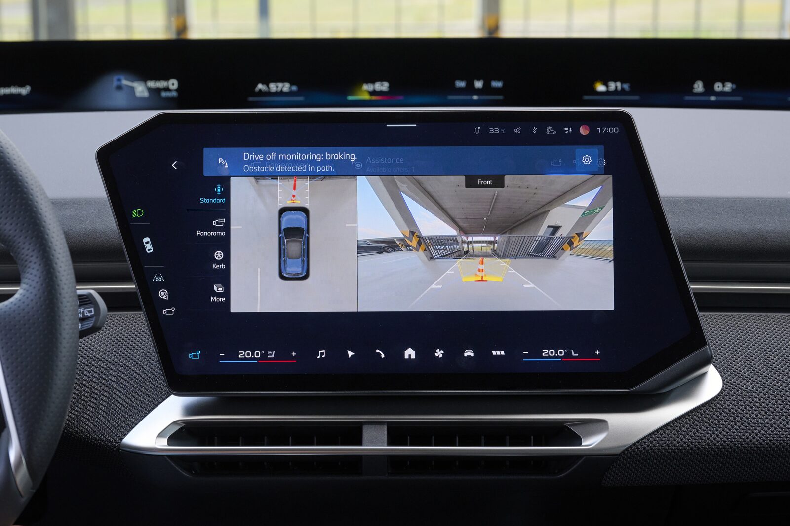 Centraldisplayen i en BMW visar meddelandet om startövervakning som bromsar för ett hinder framför bilen