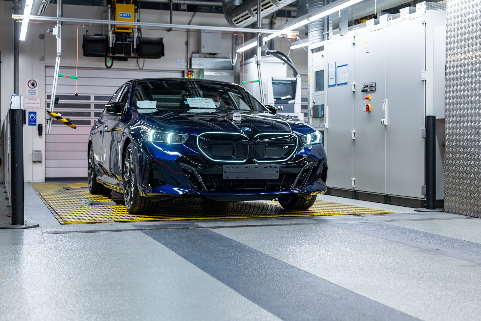 Mörkblå BMW i5 i slutkontrollens ljustunnel i fabriken i Dingolfing