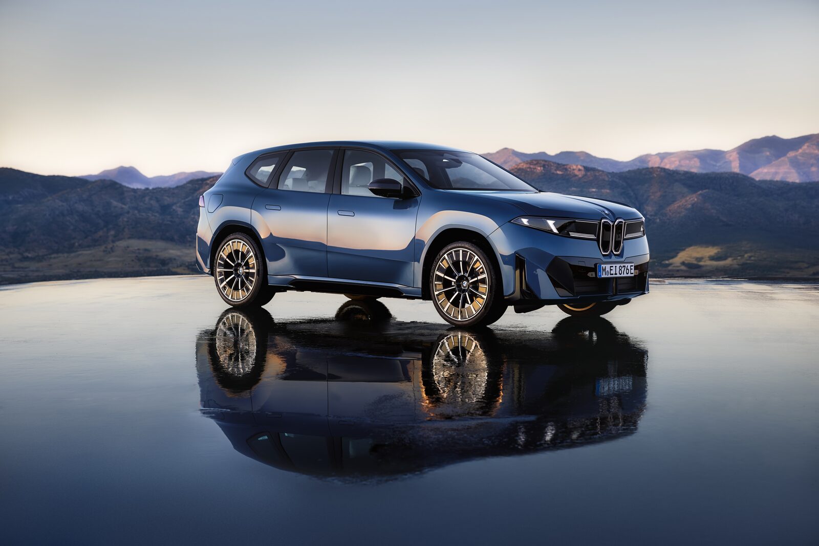 BMW iX3 i mörk lack fotograferad i skymning med bergssiluetter i bakgrunden