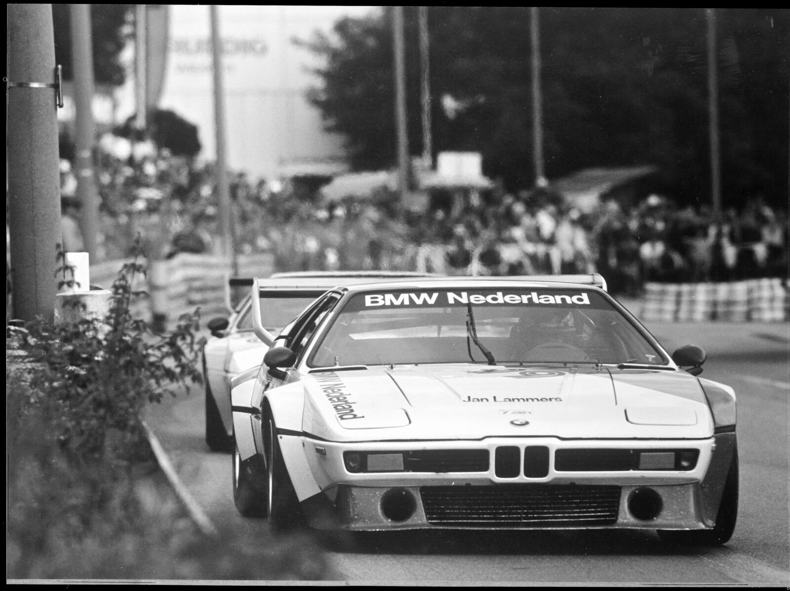 Svartvitt foto av tre BMW M1 Procar tätt efter varandra på Norisrings gatubana 1980 med publik längs banan