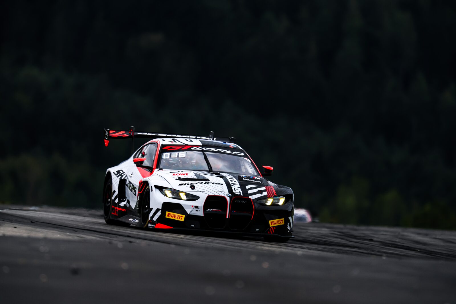 Vit och svart BMW M4 GT3 EVO med startnummer 32 fotograferad rakt framifrån på Nürburgrings asfalt med mörk granskog bakom