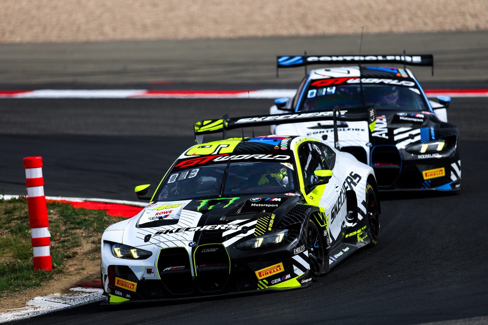 BMW M4 GT3 EVO med startnummer 46 i vit och gul lack före en annan M4 GT3 EVO genom en kurva på Nürburgring