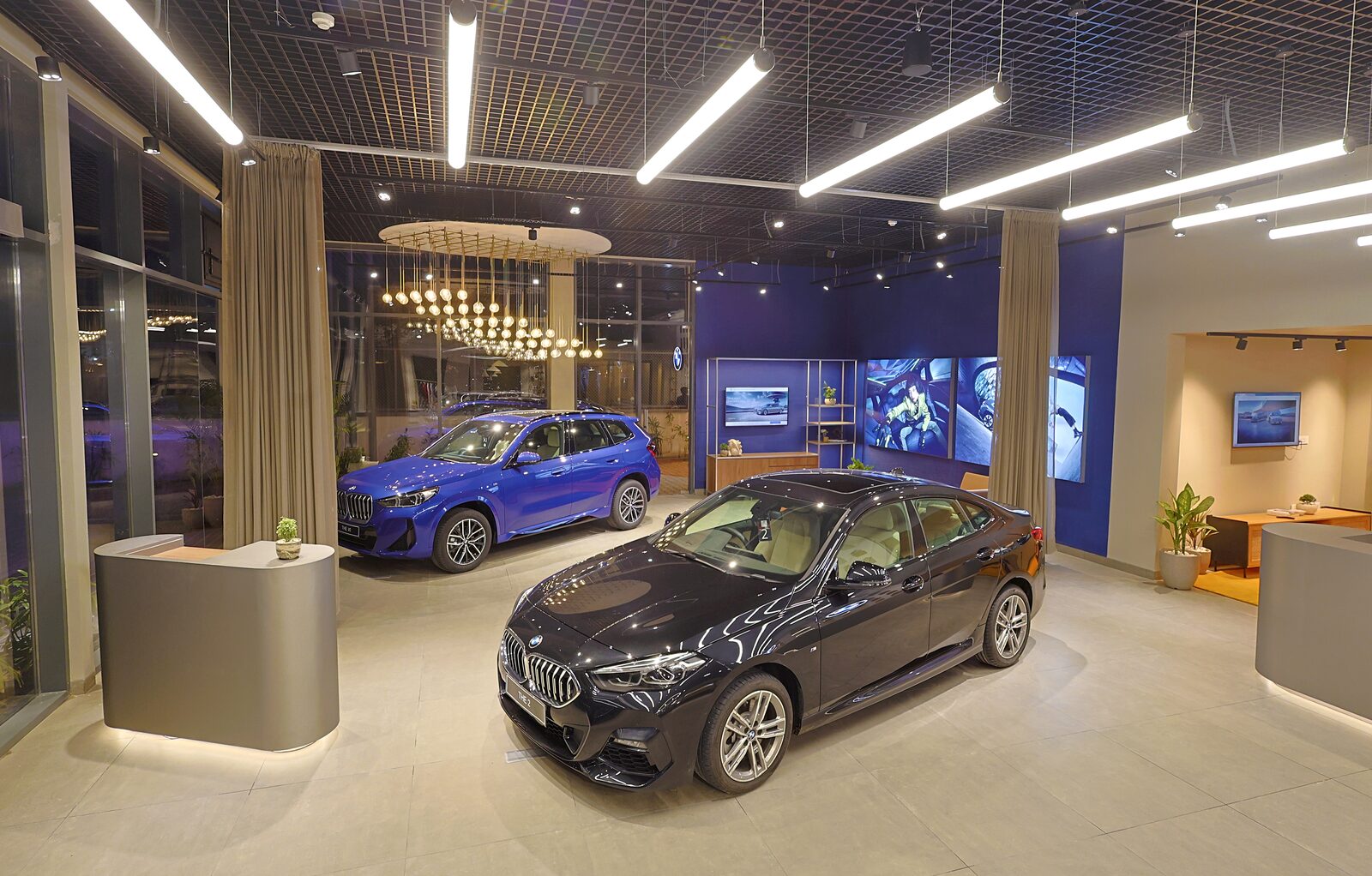 BMW-bilhall med en blå X1 och en mörk 2-serie Gran Coupé under upplyst innertak