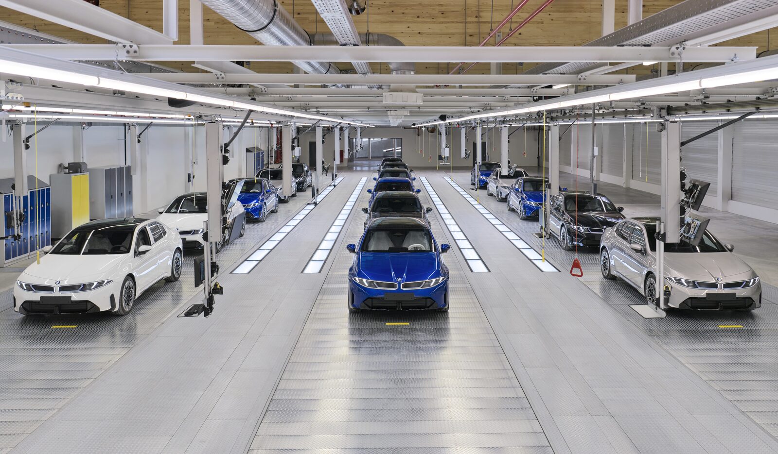 Blå BMW i3 mitt i en ljus monteringshall i München med rader av färdiga bilar på båda sidor