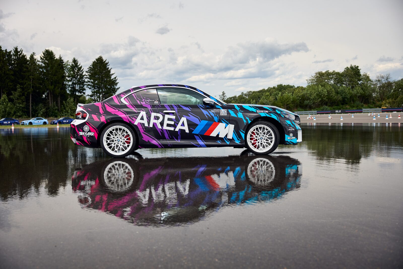 BMW M2 Drift Signature i AREA M-dekor står på en spegelblank vattenyta med sin egen spegelbild under sig