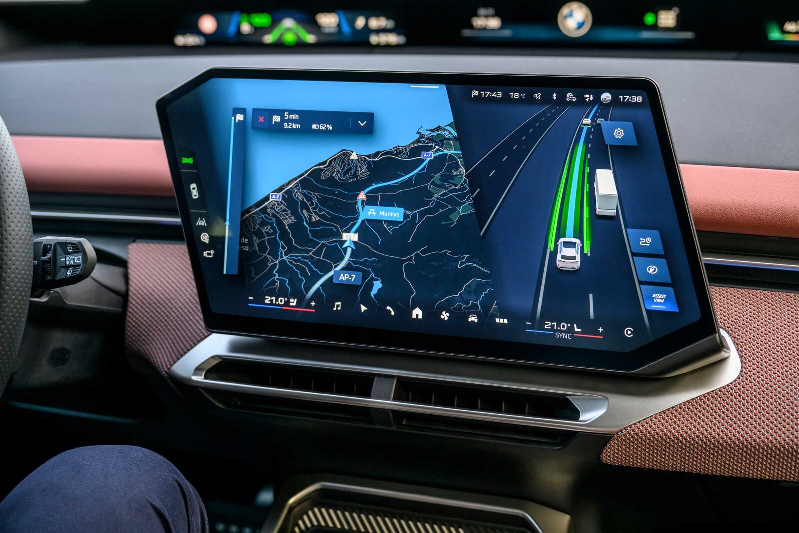 Centerdisplayen i en BMW iX3 visar Assist View med körfältsgrafik och en lastbil i intilliggande fil