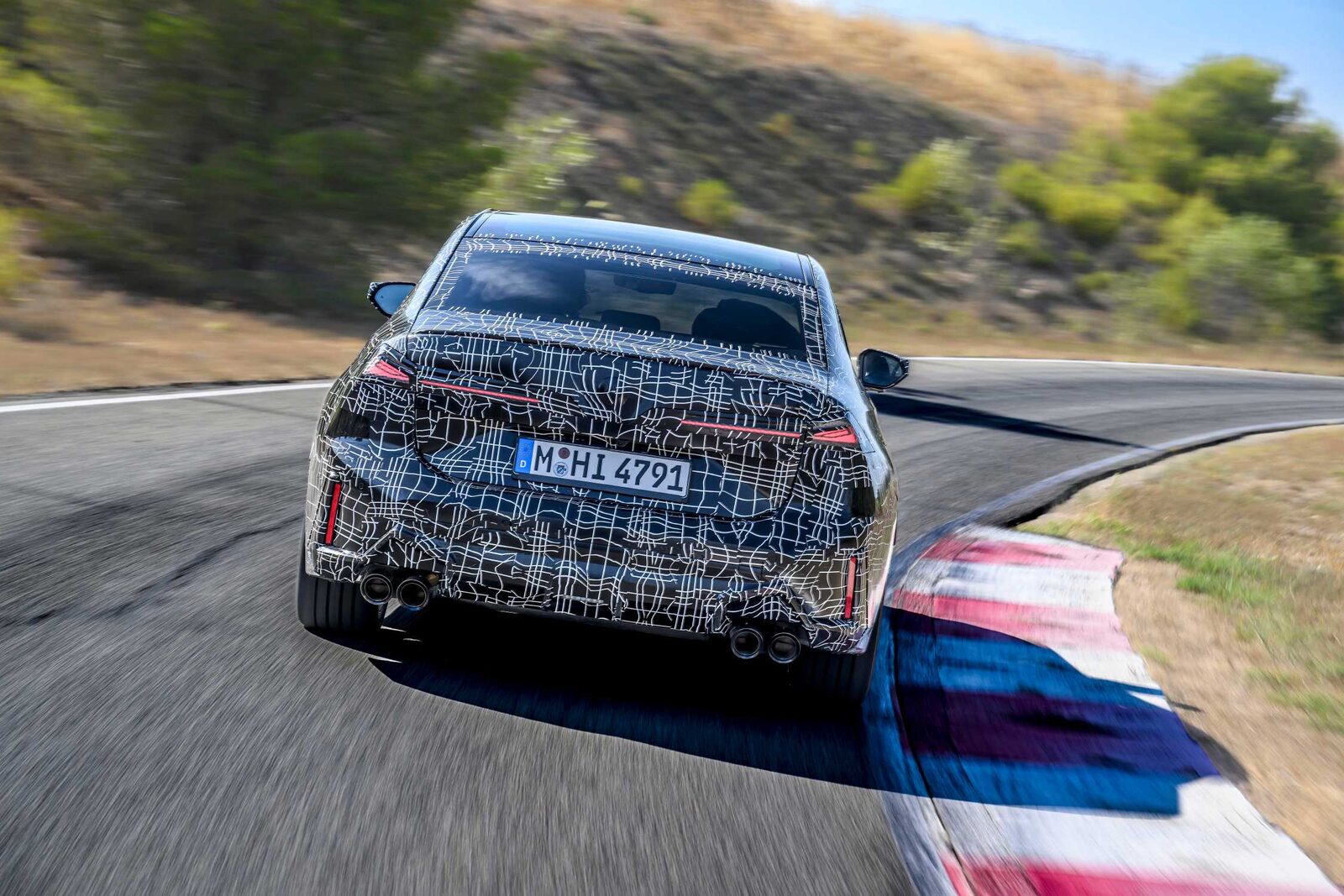 Kamouflerad BMW 3-serie-prototyp bakifrån på banan med fyra avgasrör och smala bakljus
