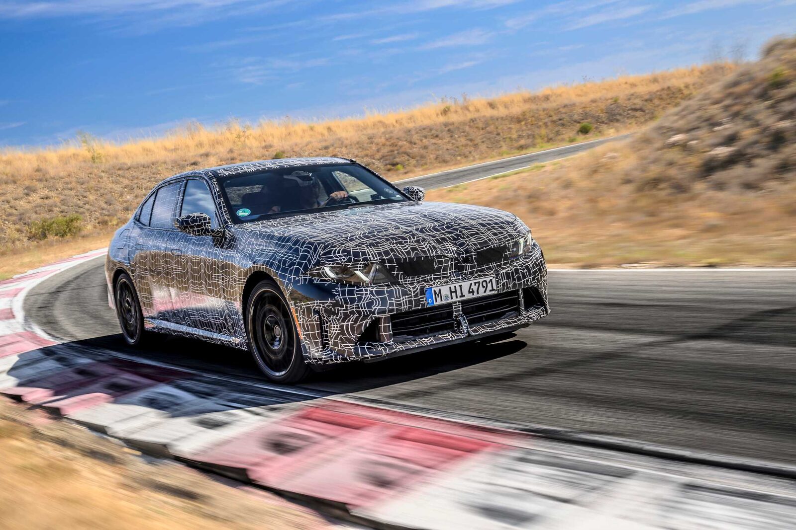 Kamouflerad BMW 3-serie-prototyp i en snäv kurva på testbanan i Miramas