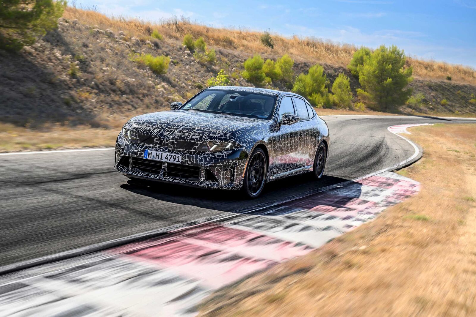 Kamouflerad BMW 3-serie-prototyp accelererar ut ur en kurva på banan i Miramas