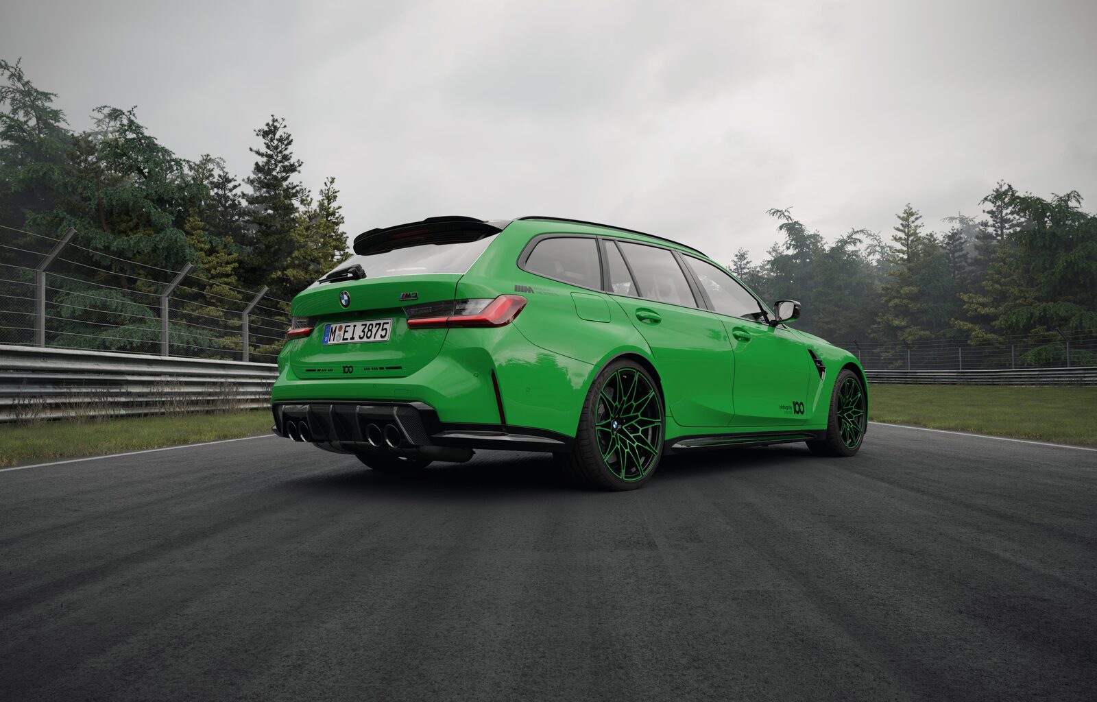 BMW M3 Touring i Nürburgring Green snett bakifrån på banan med ljust tak, gröna fälgar och 100-emblem på bakpartiet