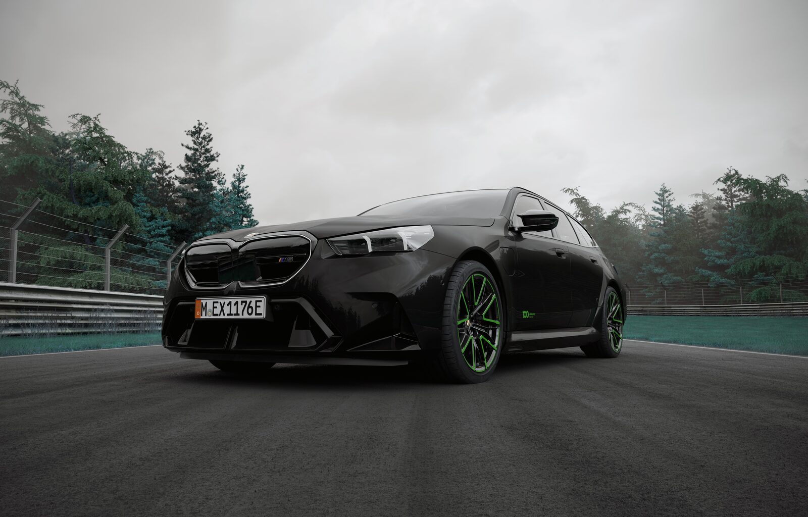 BMW M5 i Black Sapphire metallic snett framifrån med gröna fälgaccenter och Nürburgring 100-dekal på framskärmen