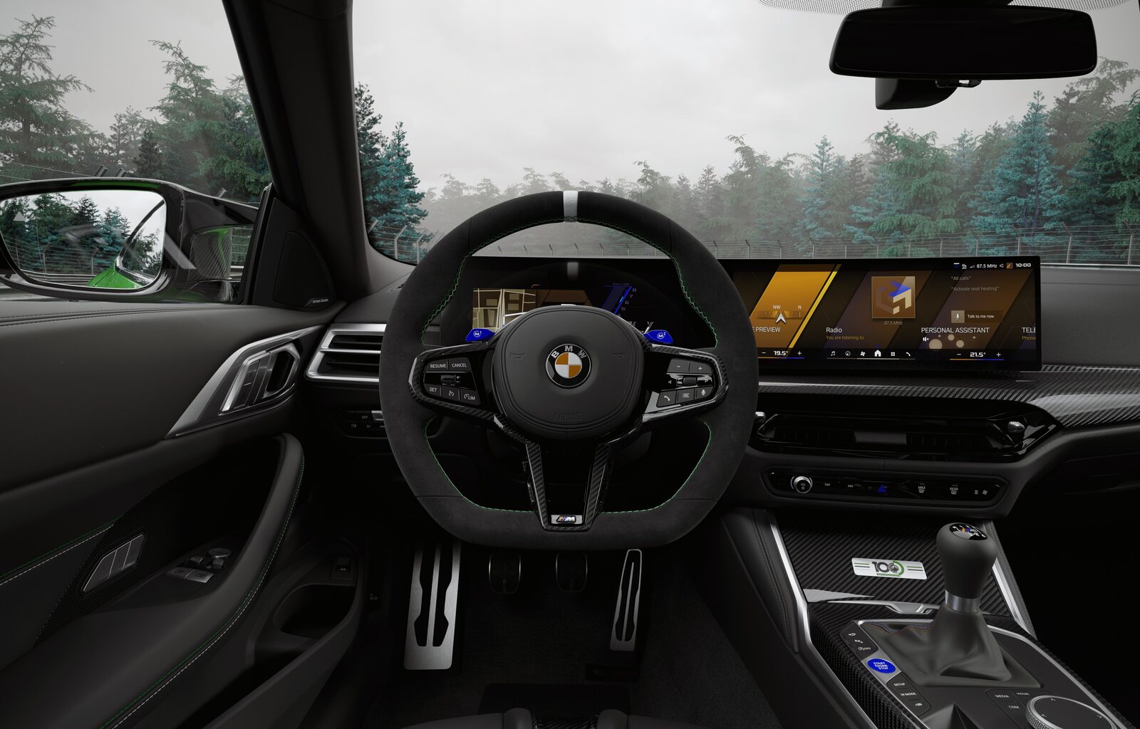 Interiör i jubileumsbilen med M-ratt i Alcantara, gröna säkerhetsbälten och BMW Panoramic iDrive-skärm