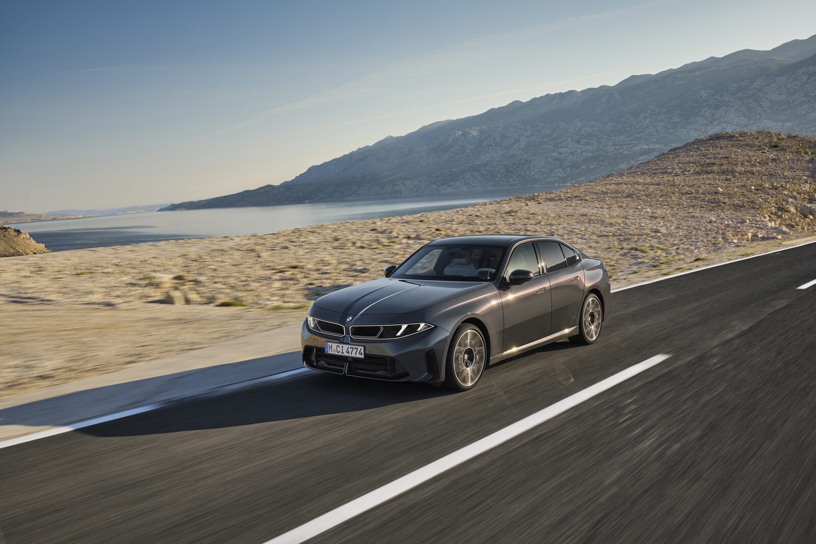 Grå BMW 320 snett framifrån i fart på landsväg