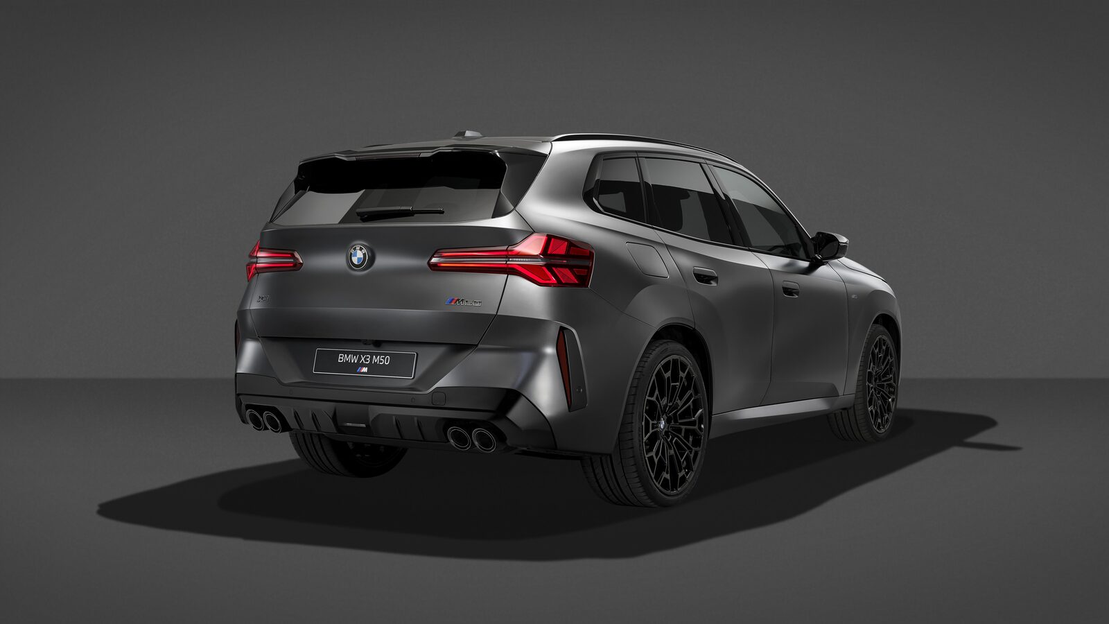 BMW X3 M50 xDrive med Black Package bakifrån snett från sidan med fyra avgasrör och svarta emblem