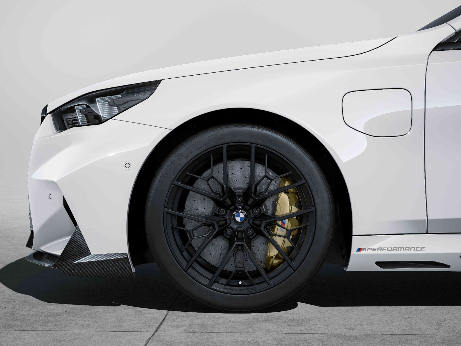 Vit BMW M5 med svarta 1075 M-fälgar i Jet Black och gula bromsok, fotograferad från sidan