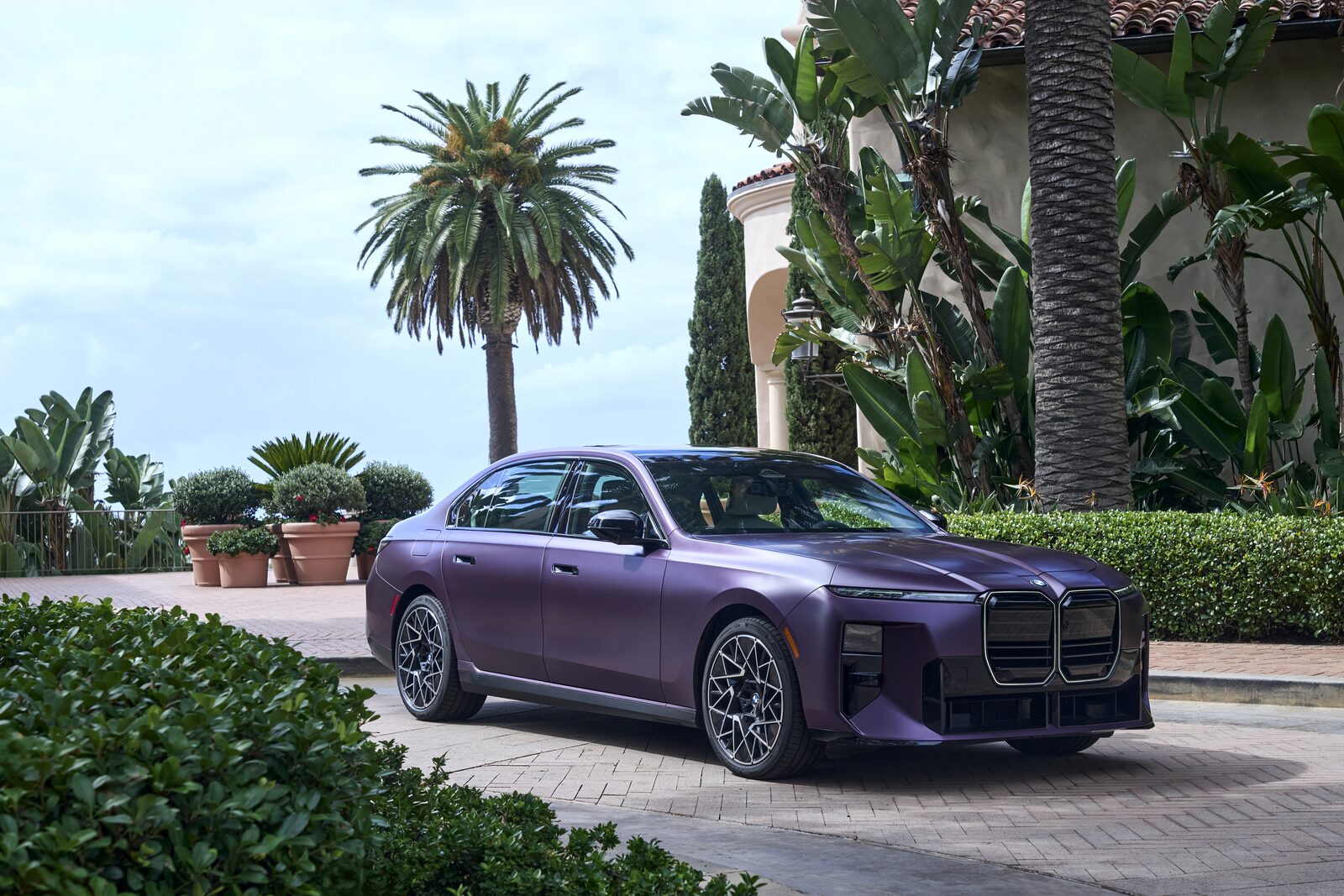 Mattlila BMW 7-serie med M Sport-paket framför en villa med palmer i Los Angeles