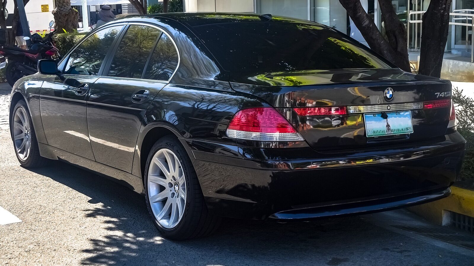 Svart BMW 745i E65 snett bakifrån med den höga bagageluckan som ligger ovanpå bakskärmarna och de uppåtvinklade baklyktorna